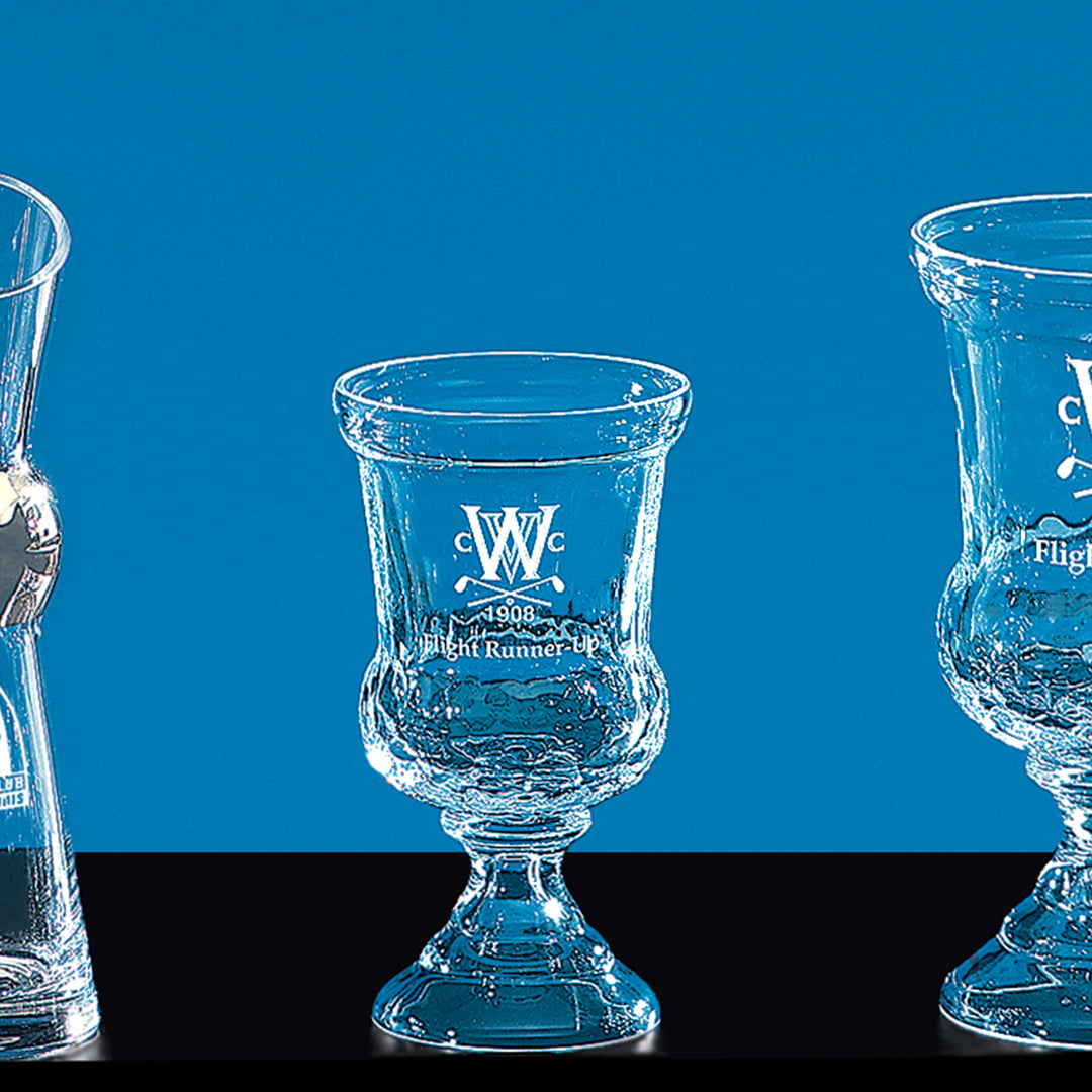 Three Crystal Warrington Trophies by Prize Possessions stand on a black surface against a blue background. Each trophy features etched text, logos, and ornate styling—ideal corporate awards for recognition ceremonies.