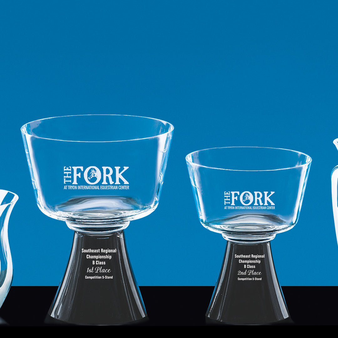 Two Harmony Bowl trophies by Prize Possessions, with clear glass bowls and black footed bases, featuring The Fork logo, are set against a blue background. The larger one stands out; both honor the Southeast Regional Championship 1st Place.