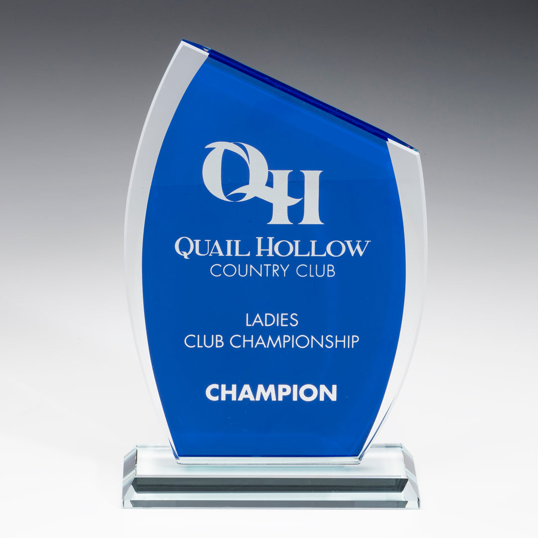 The Blue Glass Azure Award by Prize Possessions features "Quail Hollow Country Club Ladies Club Championship Champion" engraved in white on blue glass and stands on a clear rectangular base—ideal for corporate or employee recognition.