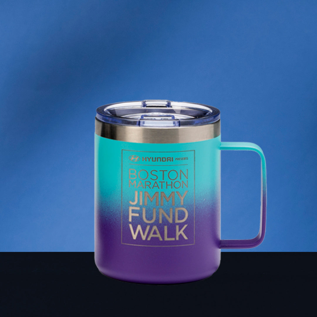 A Blue/Purple Travel Mug with Handle by Prize Possessions, featuring gold text, rests on a dark surface against a blue background. The mug has a clear lid and displays Boston Marathon Jimmy Fund Walk and Hyundai branding.
