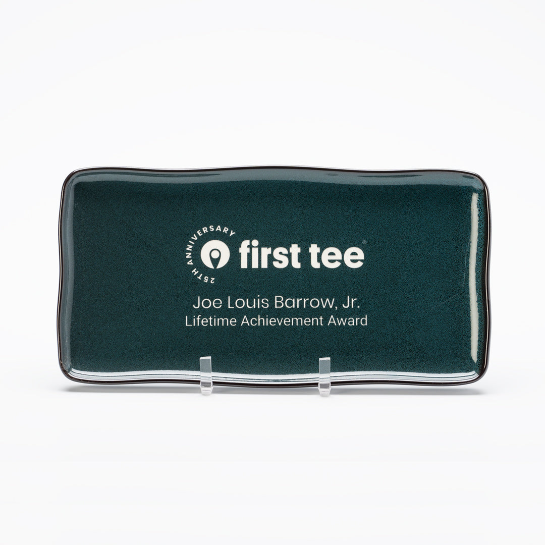 A rectangular Ceramic Midnight Blue Luna Platter by Prize Possessions, displayed on a clear stand with the First Tee logo and "Joe Louis Barrow, Jr. Lifetime Achievement Award" text against a white background.