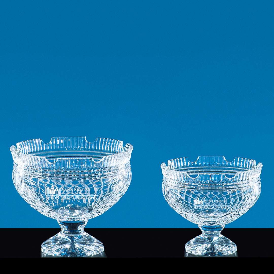 Two Prize Possessions Crystal Footed Liberty Bowls, one larger than the other, are displayed side by side on short pedestals against a solid blue background, creating a striking awards display.
