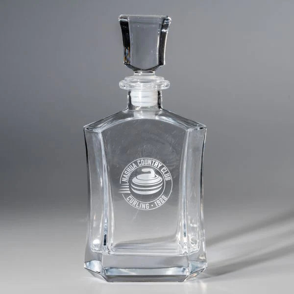 The Crystal Paola Decanter by Prize Possessions features a square stopper and is engraved with "Imesona Country Club Curling 1929" plus a curling stone logo, making it an elegant barware addition. Shown on a plain gray background.