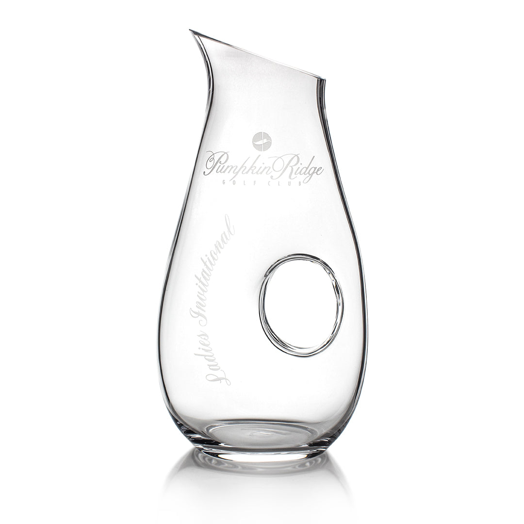 The Crystal Pierced Pitcher by Prize Possessions is a clear crystal glassware piece with an angled spout, central circular hole, and engraved text: Pumpkin Ridge Golf Club and Golfer Invitational.