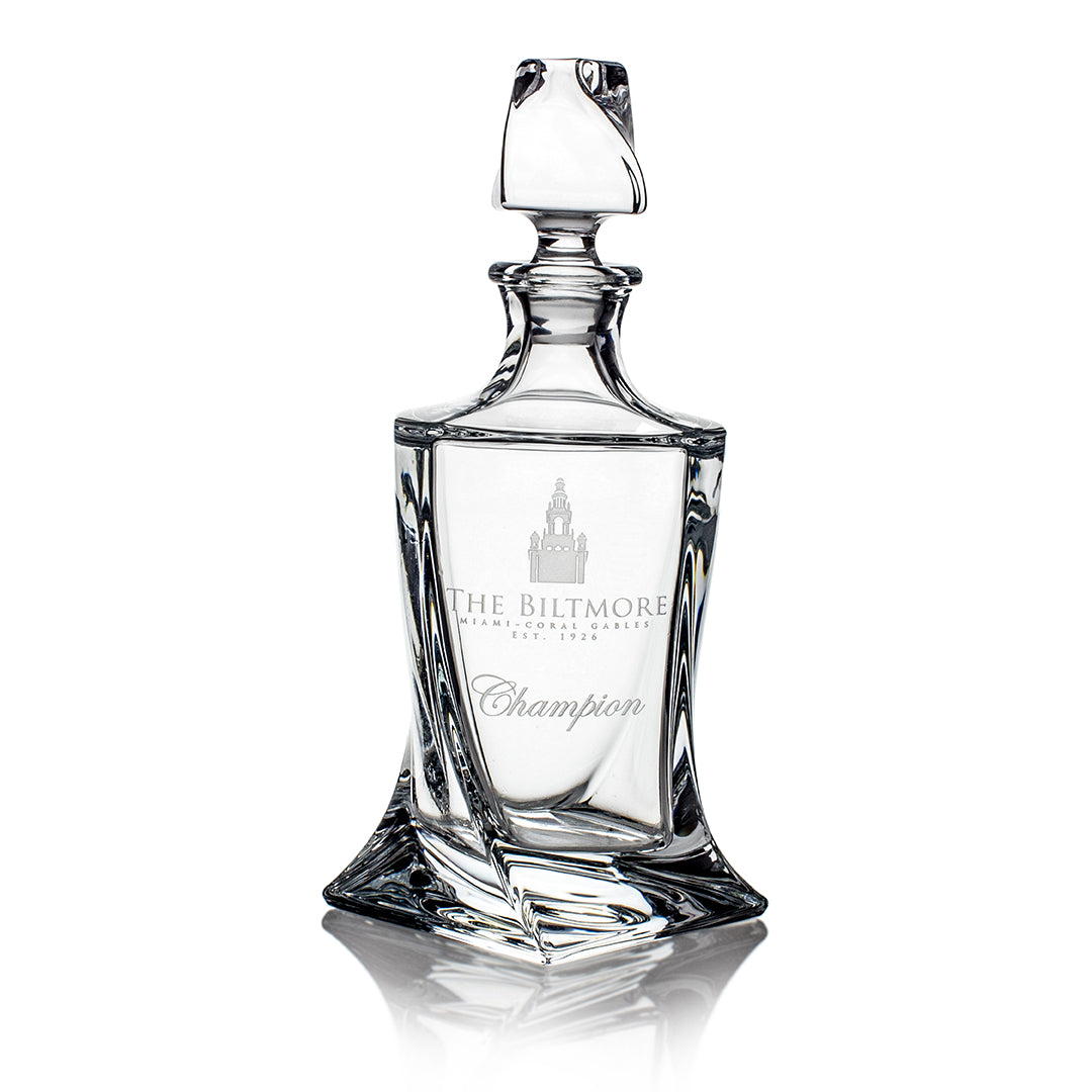 The Crystal Quadro Decanter by Prize Possessions features intricate engraving with "THE BILTMORE Champion" and a building illustration, topped with a stopper—an elegant piece to highlight your crystal glassware collection.
