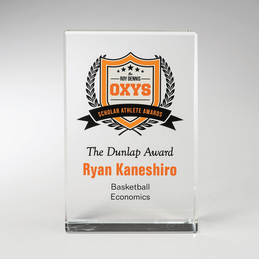 The Prize Possessions Crystal Vertical Award showcases a black and orange shield logo with Roy Dennis OXYS Scholar Athlete Awards and custom engraving: The Dunlap Award, Ryan Kaneshiro, Basketball, Economics—ideal for standout corporate recognition.