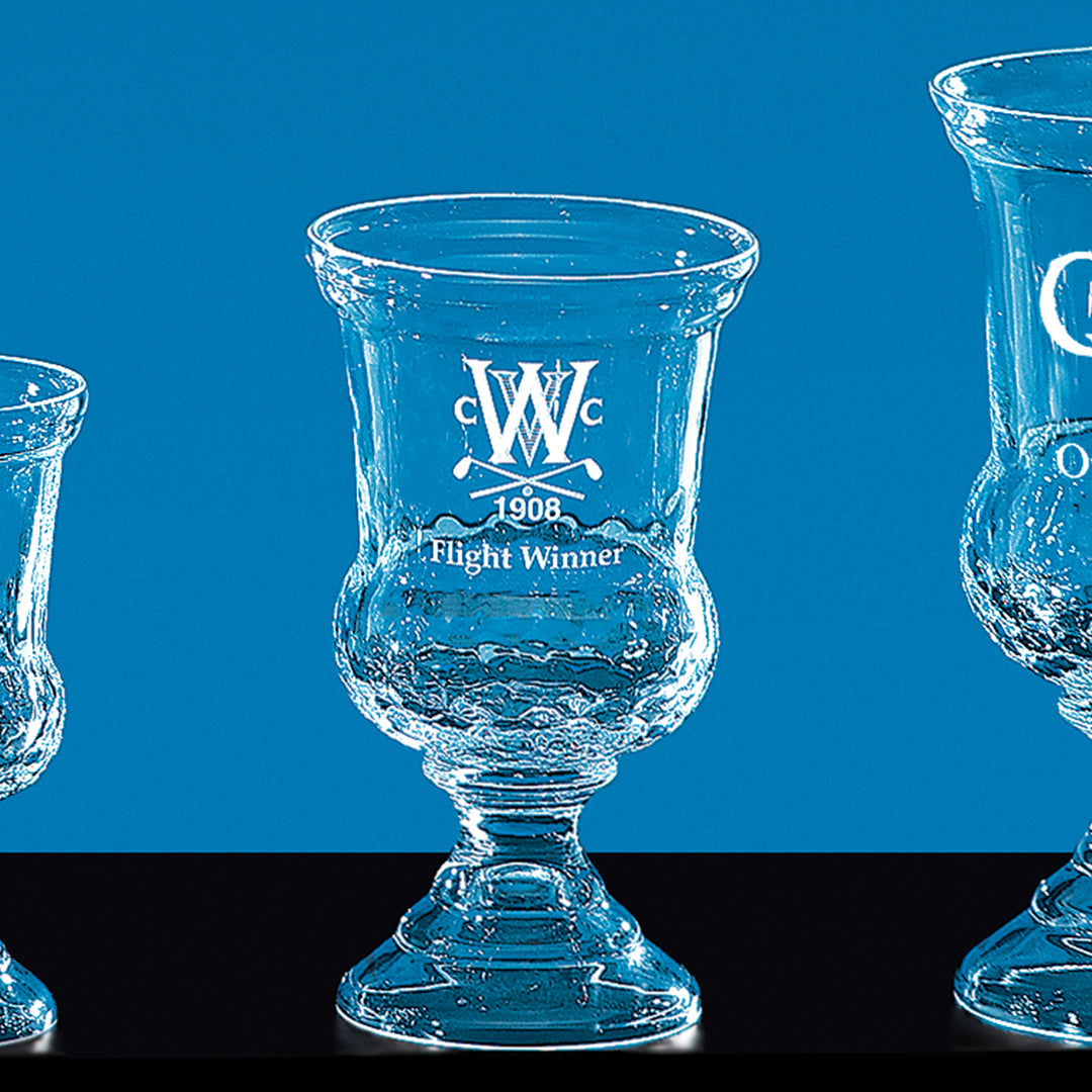 Three Prize Possessions Crystal Warrington Trophies with ornate stems are displayed against a blue background. The center trophy, reading "WCC 1908 Flight Winner," stands out as a distinguished corporate award. Only portions of the side trophies are visible.