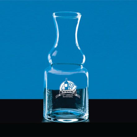 A Crystal Wine Carafe by Prize Possessions, featuring a logo with playing cards and "9th Annual Tuck Invitational" text, sits on a black surface against a blue background filled with water.