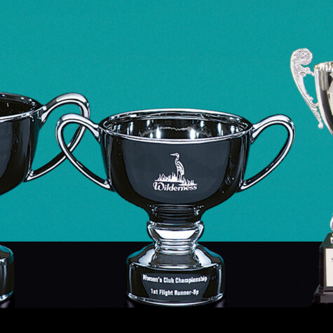 Three Ebony Ceramic Bowls by Prize Possessions are displayed on a matte-black surface against a teal background. The center bowl, larger than the others, is engraved with "Wilderness and Womens Club Championship 1st Flight Runner-Up.