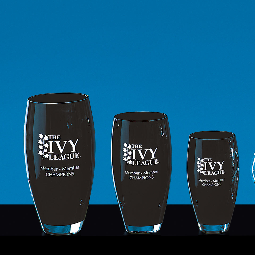 Three Ebony Crystal Vases by Prize Possessions, each featuring the Ivy League logo and “Member - Member Champions” in white, stand as a striking glass centerpiece on a glossy black surface against a solid blue background.