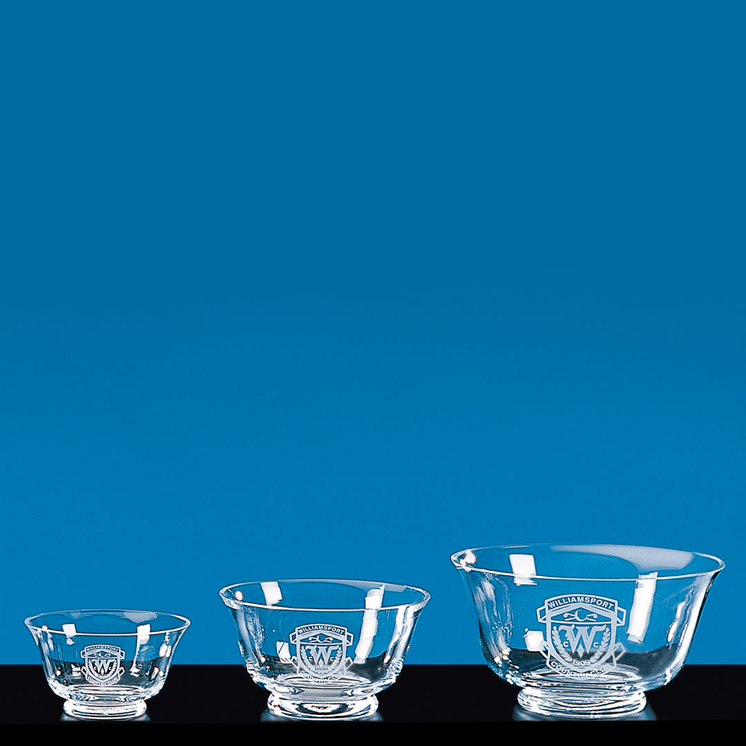 Three Prize Possessions Glass Revere Bowls, each with a matching emblem, are displayed side by side on a black surface against a blue background. Ideal as centerpiece bowls or for showcasing decorative crystal accents.