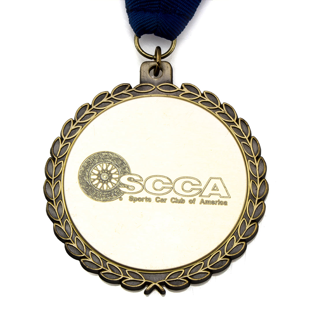The Prize Possessions Gold Medal features a laurel wreath border, a blue ribbon, and the SCCA Sports Car Club of America logo with engraved text—ideal for recognition at award ceremonies.