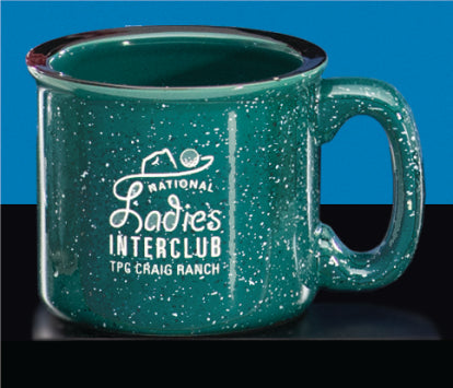 The Green Campfire Mug by Prize Possessions is a speckled green mug with a handle, featuring white "National Ladies Interclub TPC Craig Ranch" text, shown on a blue and black background.