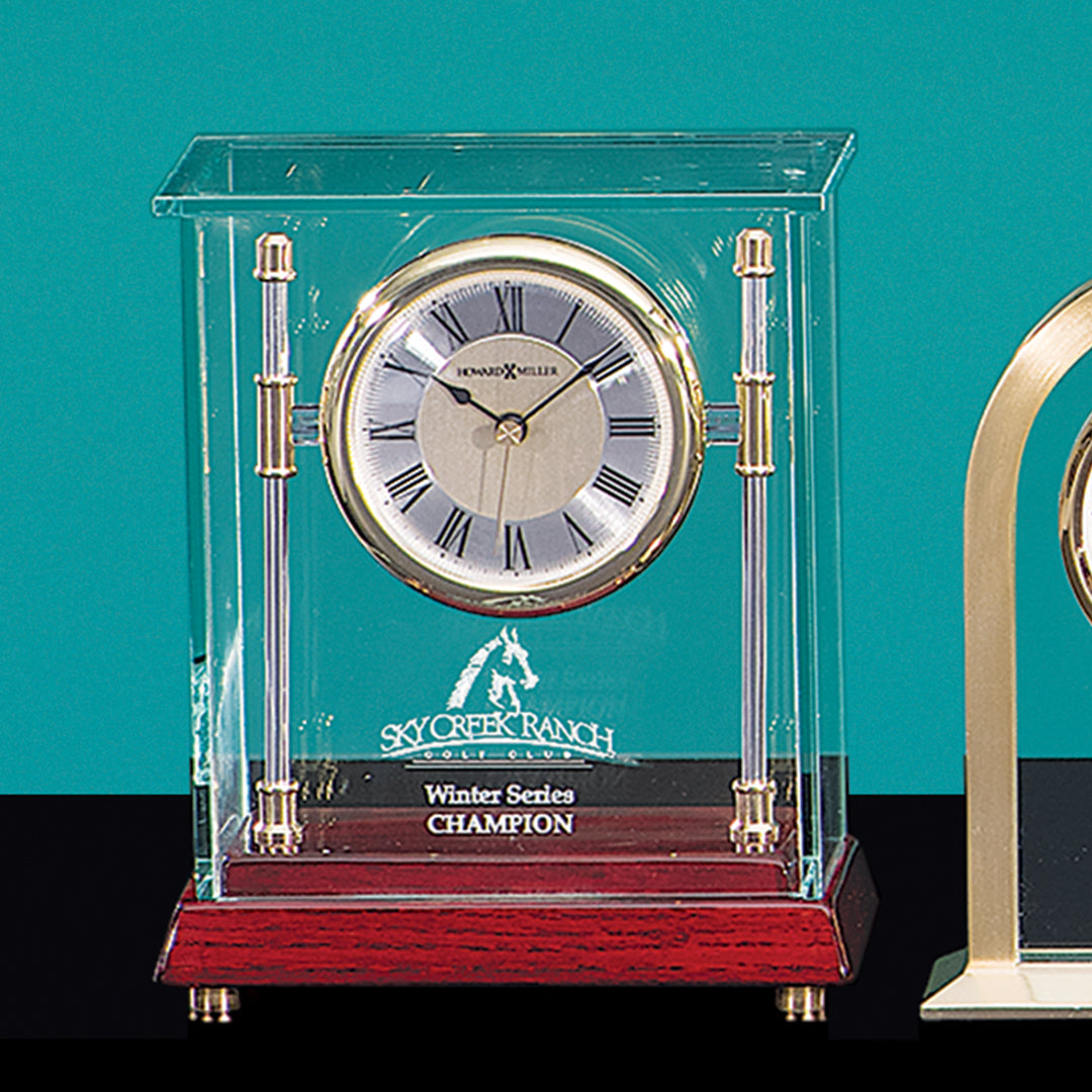 The Kensington Clock by Prize Possessions is a plaque-style clock with glass and wood accents, Roman numerals, and sits on a wooden base. The engraving reads Sky Creek Ranch Winter Series CHAMPION with a horse graphic.