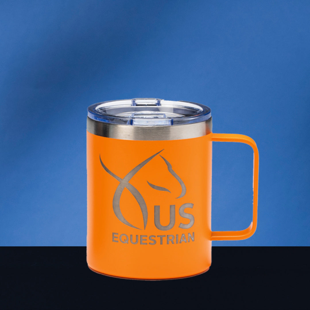 The Prize Possessions Orange Travel Mug with Handle features a metal rim, transparent lid, and a minimalist horse head logo with "US EQUESTRIAN" in silver, set against a blue background on a black surface.