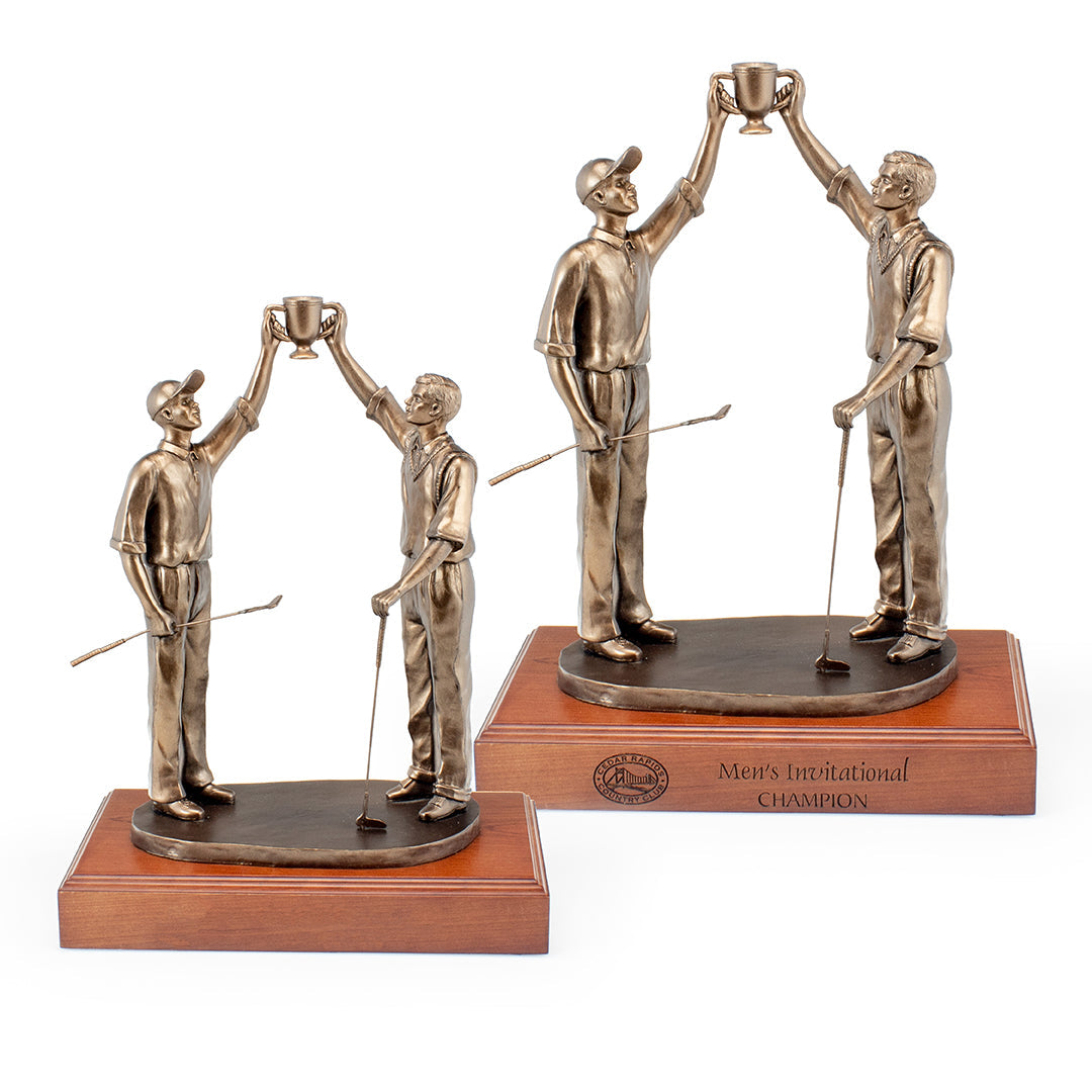 The Partners V Statue by Prize Possessions features two bronze male golfers holding clubs and a cup, standing on a wooden base—perfect as a corporate recognition trophy or elegant office decor. One base is inscribed “Men’s Invitational Champion.”.