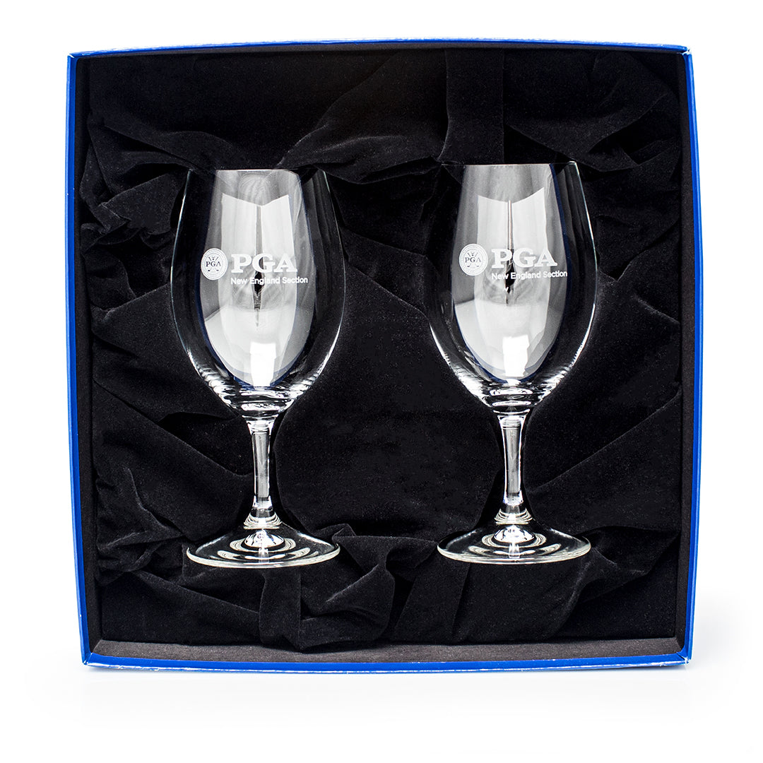 The Prize Possessions Riedel Overture Magnum Wine Glass Gift Set (2 ea. 1612) features two clear glasses with PGA and logo etching, elegantly presented upright in a black velvet-lined blue box—a perfect gift for wine lovers.