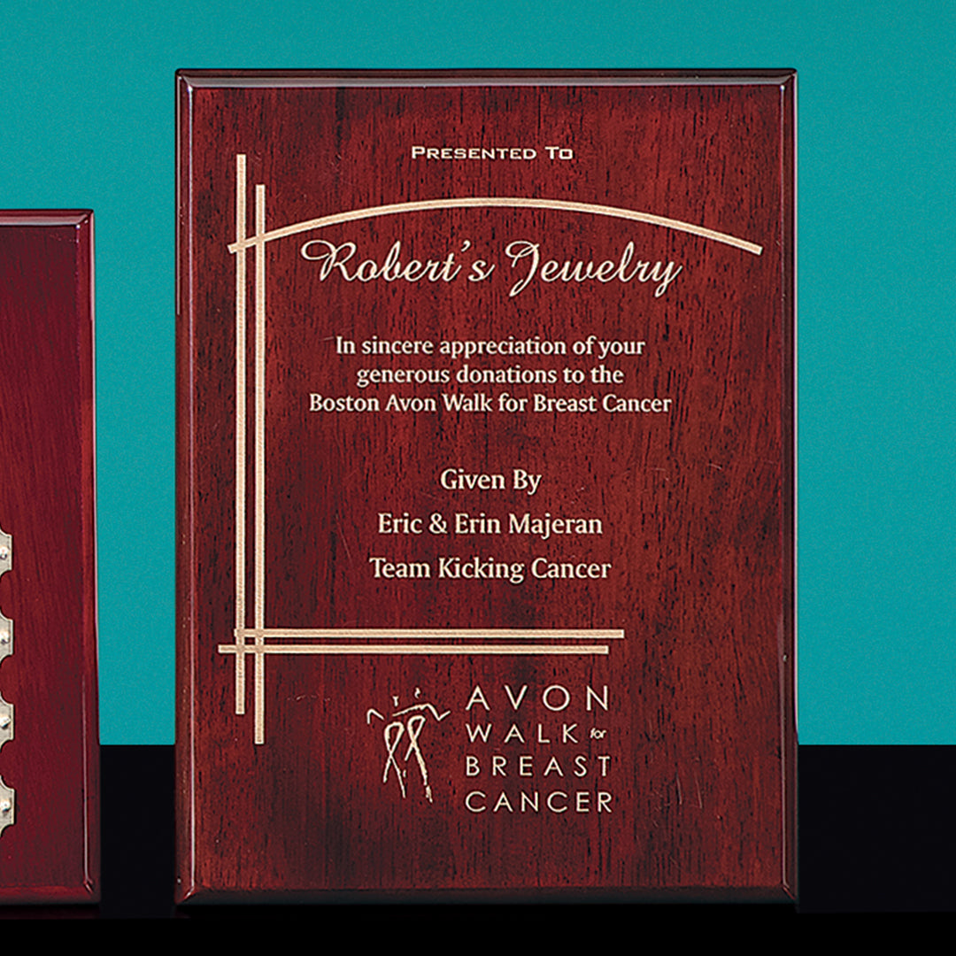 A Prize Possessions Rosewood Plaque with gold text: Presented to Robert’s Jewelry in sincere appreciation of your generous donations to the Boston Avon Walk for Breast Cancer. From Erin & Kick Majeran, Team Kicking Cancer.
