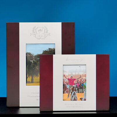 Two Prize Possessions Rosewood and Silver Frames are displayed against a blue background. Each frame holds a different photo: one featuring a landscape, the other showing a person celebrating outdoors.