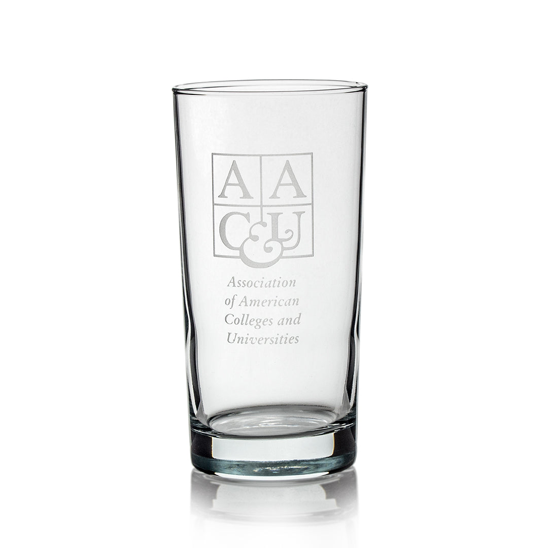 The Prize Possessions Round Highball Glass features the Association of American Colleges and Universities logo etched on the front—ideal for highball cocktails and displayed elegantly on a white background.