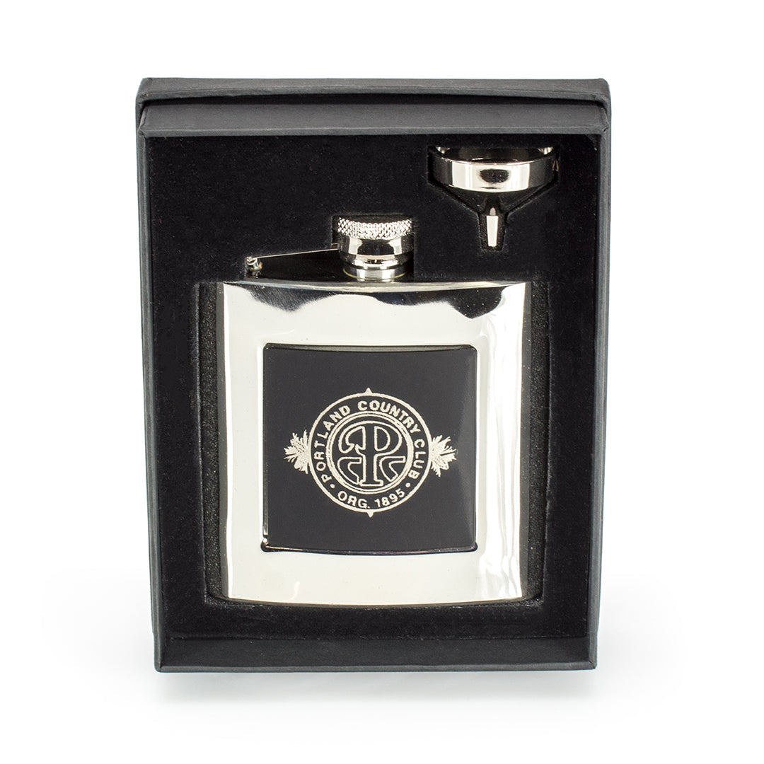 The Prize Possessions Silverplate Flask features a sleek design with a black accent and the Portland Country Club logo, and comes in a black gift box with a metal funnel—an ideal barware accessory for any occasion.