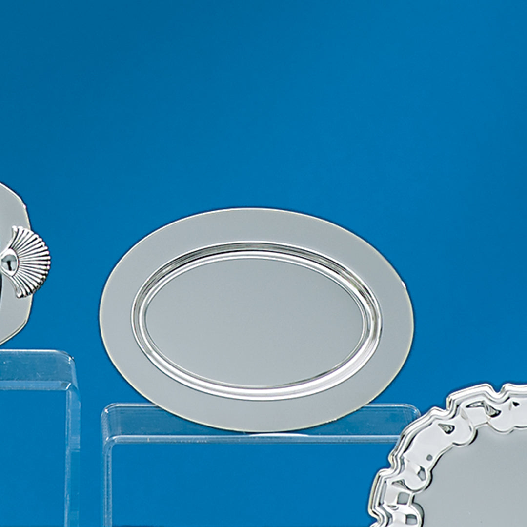 Three Prize Possessions Silverplate Trays are displayed on clear stands against a bright blue background. The center tray is oval, while the decorative trays on the sides are partially visible.