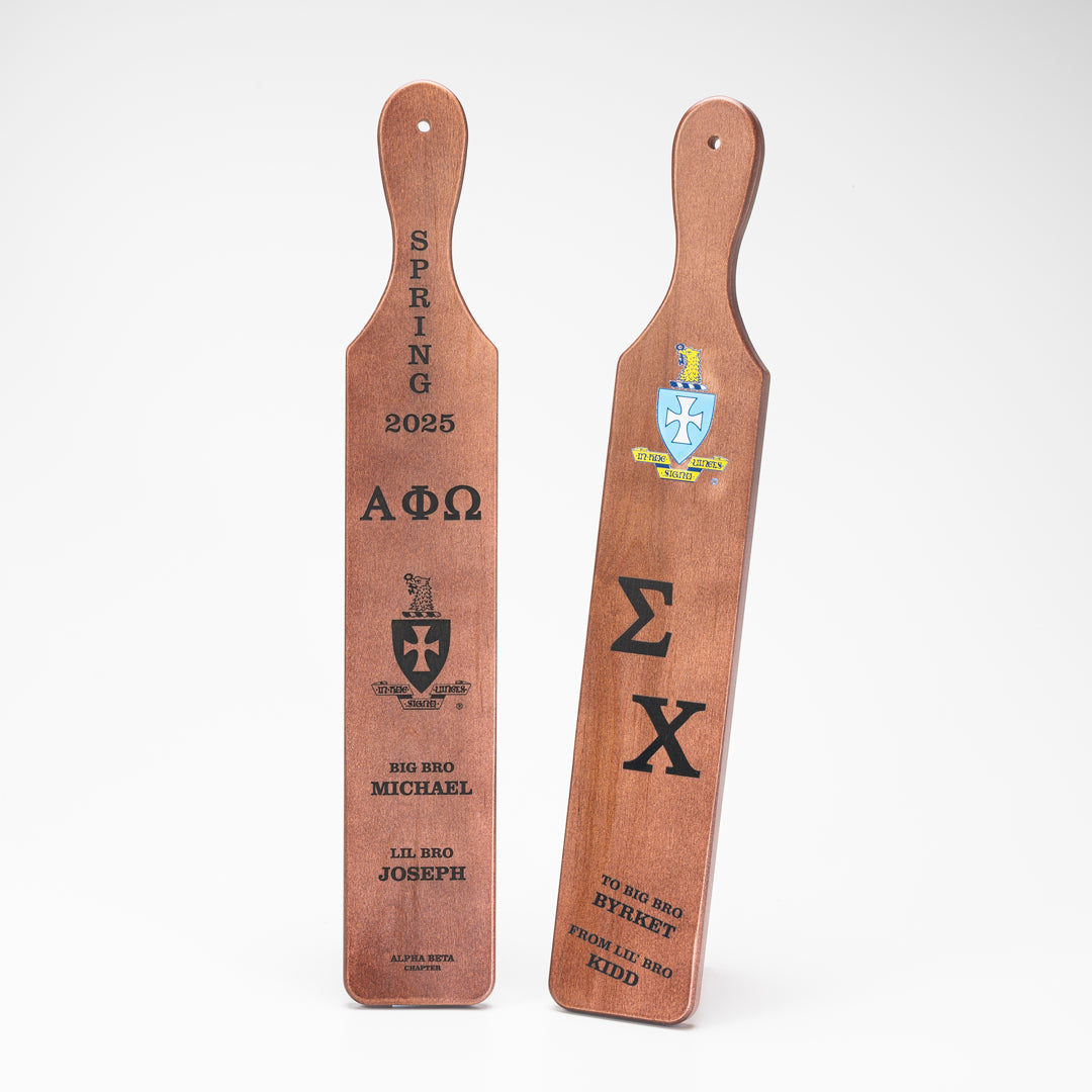 Two Prize Possessions Wood Fraternity Paddles engraved with Greek letters, crests, and personalized names—one reading SPRING 2025 ΑΦΩ, the other ΣΧ. A unique keepsake or gift for fraternity members.
