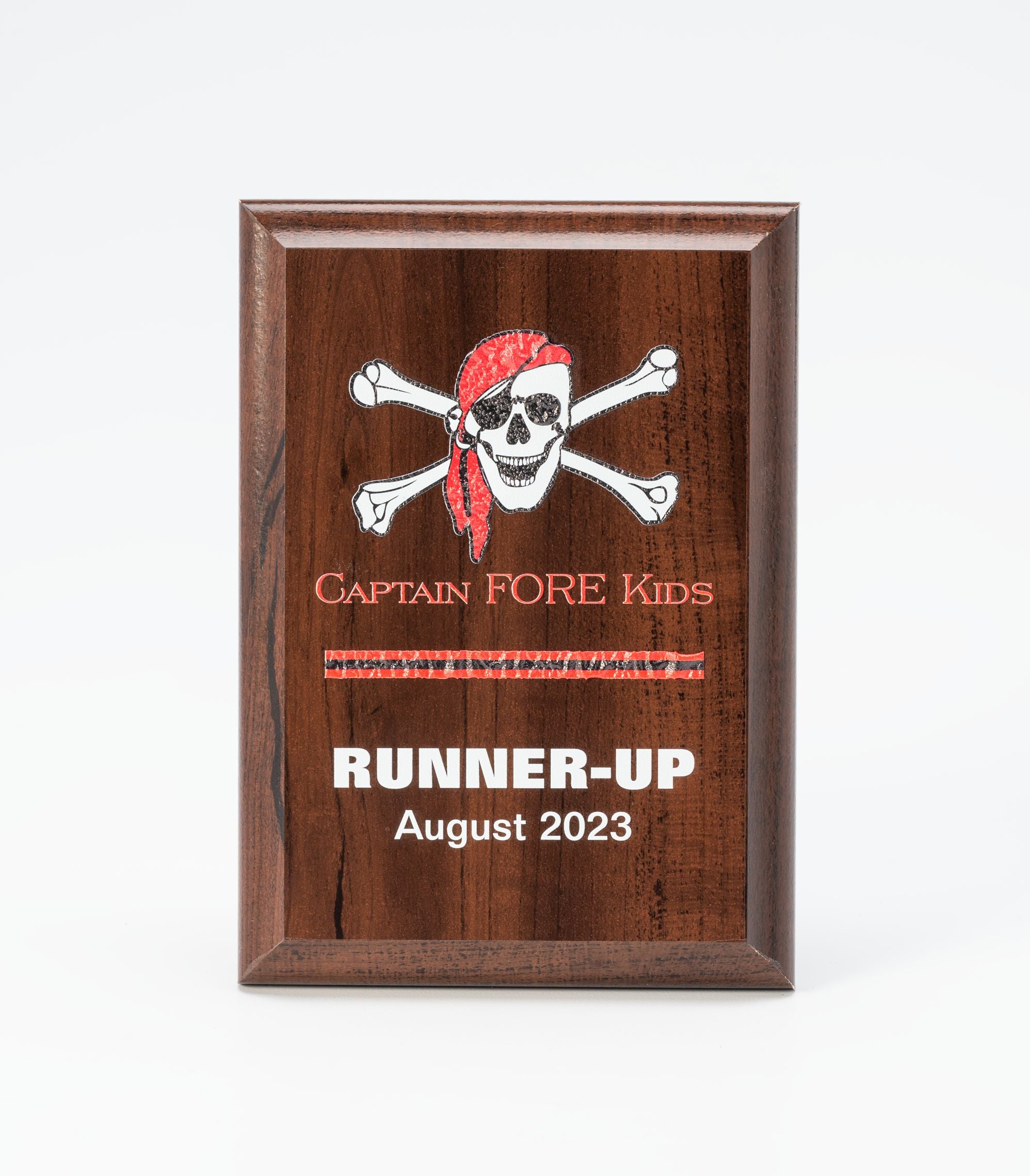 The Prize Possessions Wood Plaque features a pirate skull and crossbones with a red bandana, plus engraved signs: "Captain FORE Kids" above "RUNNER-UP August 2023.